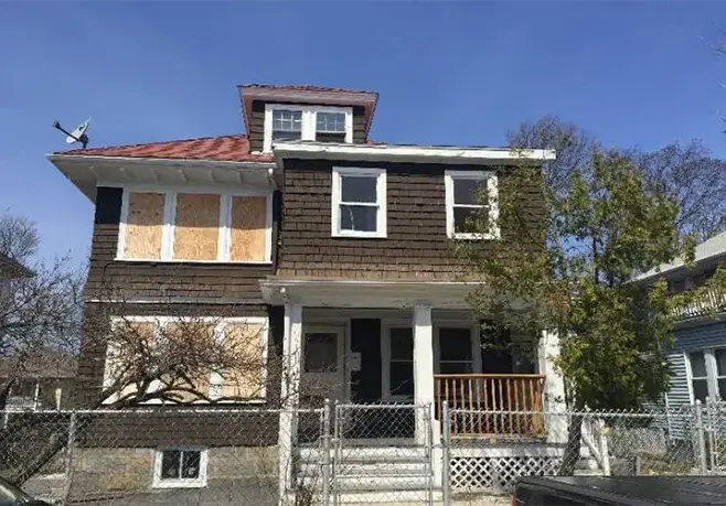 Image of boarded up brown run down house before renovation