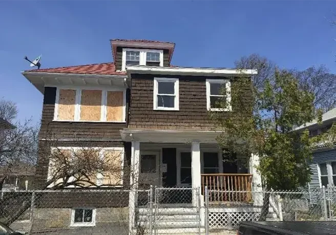 Image of boarded up brown run down house before renovation